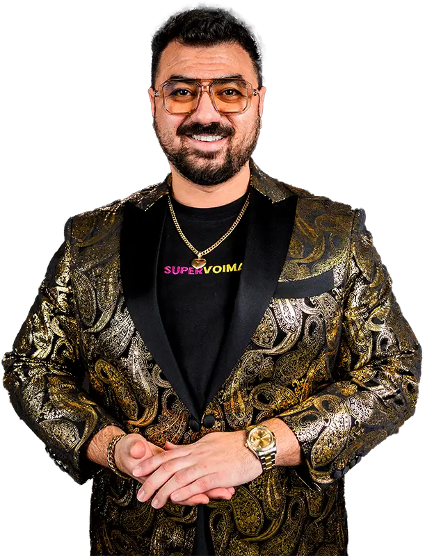 Timo Avdo katsoo kameraan. Päässä on silmälasit ja hän on pukeutunut Räätälistudio BQ:n räätälöimään esiintymistakkiin. Takki on kullan/mustan värinen.